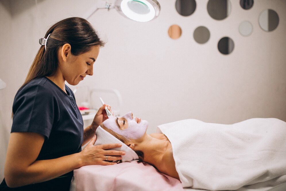 cosmetologist-applying-mask-face-client-beauty-salon_1303-16789